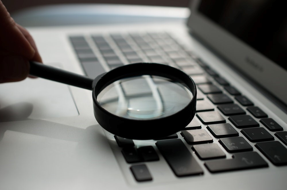 A magnifying glass inspecting a laptop.